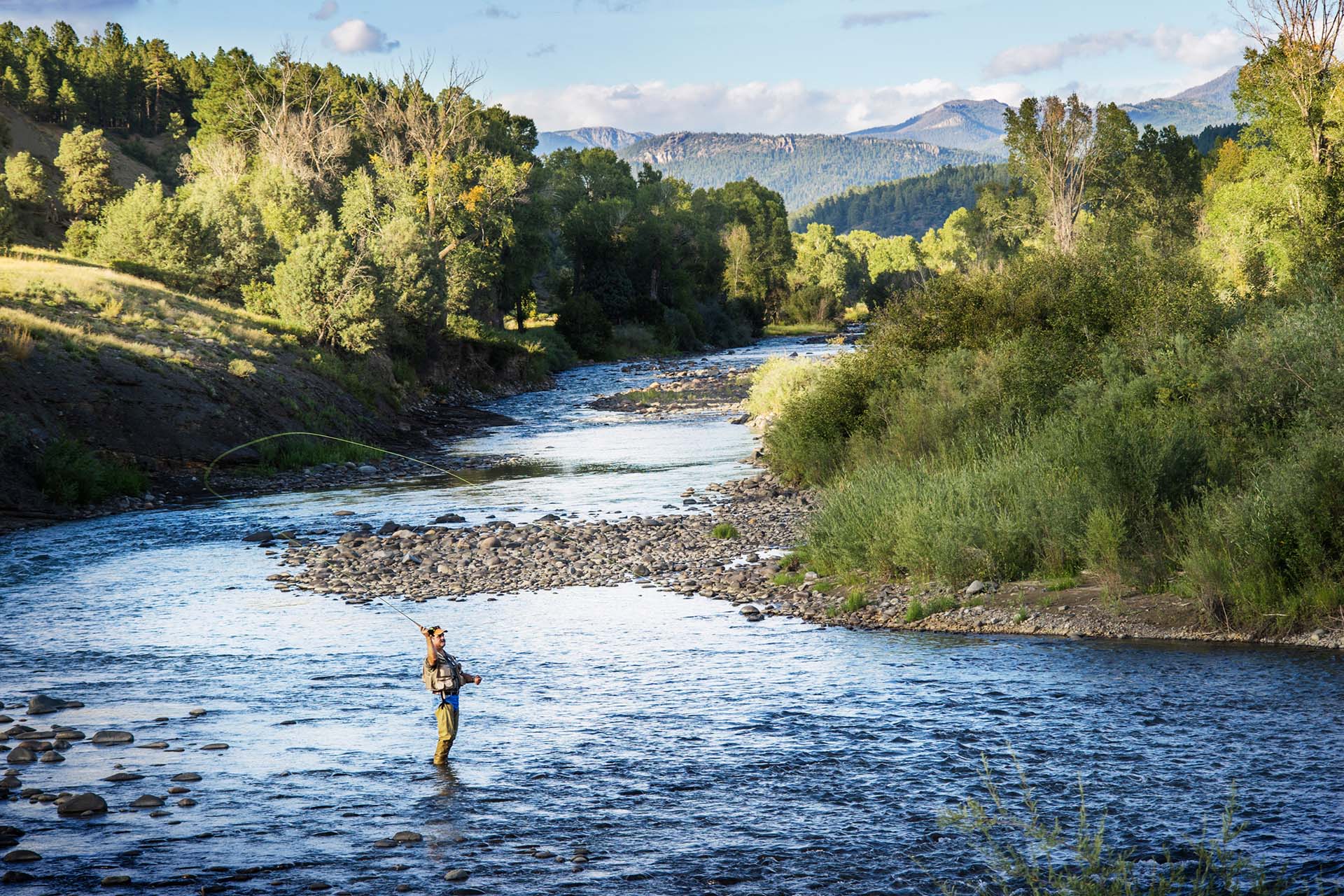 Man fly-fishing in the river near the Eagle house he found in a home search with the best real estate agent. 